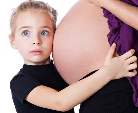 flicka som lyssnar på sin gravida mammas mage